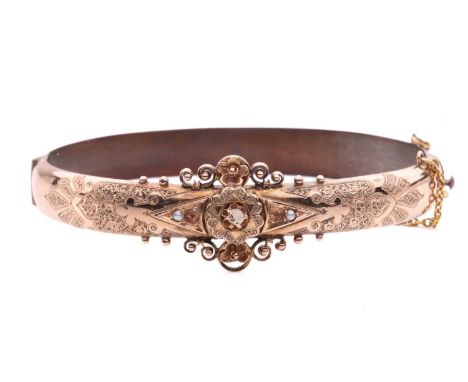 A Victorian hinged bracelet set with seed pearls, constructed with two hollow halves, where the front has been engraved with 