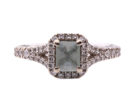 An aquamarine and diamond cluster ring in 18ct white gold, consisting of an emerald-cut aquamarine of pale blue colour, in a 