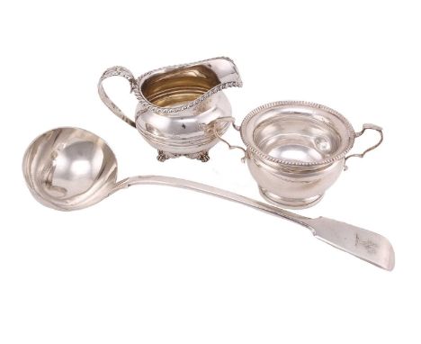 A George III silver cream jug, circular with gadrooned border and leaf-capped scroll handle, banded to belly; on four paw fee