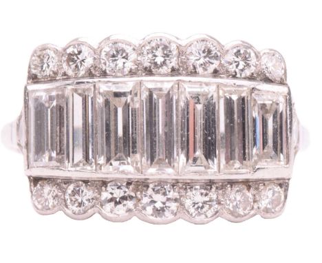 A diamond ring, set with a central row of baguette cut diamonds between rows of round brilliant cut diamonds, leading to diam