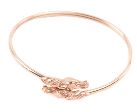 A double horse head torque bangle, with a double hollow tube construction, designed to flex open with two facing horse heads 