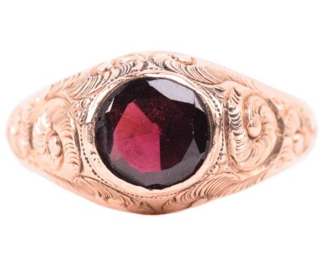An Edwardian single stone garnet ring by Ostby & Barton, set with an almandine garnet, measuring 7.8mm diameter, with scrolli