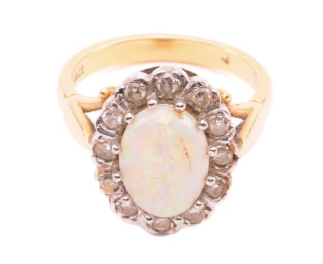 A precious opal and diamond cluster ring, featuring an opal cabochon approximately measures 11.3 x 8.3 x 3.6 mm, displaying g