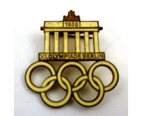 A 1936 OLYMPIAD BERLIN PIN BADGE, white enamel, in the form of the five rings beneath the Brandenburg Gate, 3cm wide 