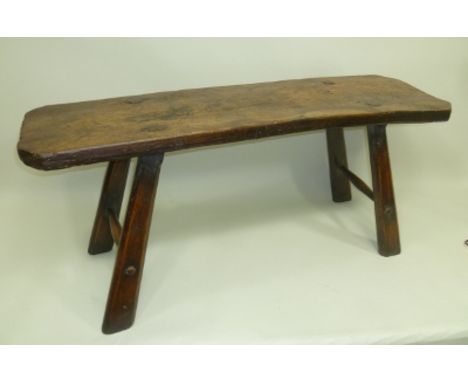 AN 18TH CENTURY RUSTIC ELM TOPPED "PIG BENCH", on four splayed legs with two plain stretchers, 49cm high x 115cm long 