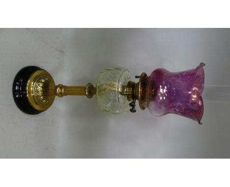 A VICTORIAN OIL LAMP, having brass stem on ebonised base, glass reservoir with pink tinted glass shade, overall 74cm high (wi