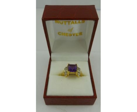 A 9CT GOLD AMETHYST AND DIAMOND DRESS RING having square cut central stone flanked by twin shoulders each set with four 8/8 c