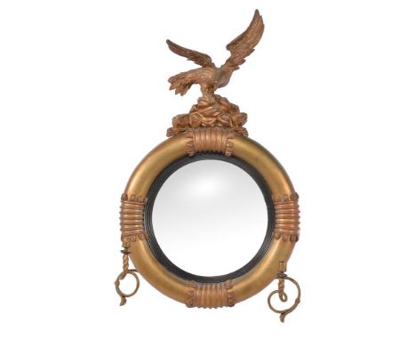 A George IV giltwood and composition convex wall mirror, circa 1830, with eagle surmount above the circular frame with ebonis