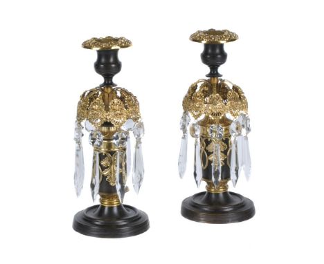 A pair of Regency parcel gilt and lacquered brass and cut glass lustre candlesticks, circa 1815, the engine milled waisted ur