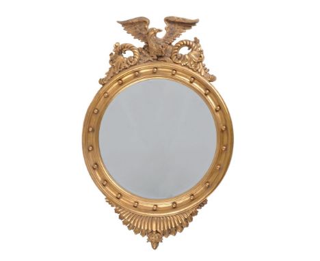A carved giltwood wall mirror in Regency taste, late 20th century, possibly by Harrison &amp; Gil, the circular plate surmoun