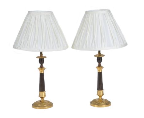 A pair of parcel gilt and lacquered metal table lamps in the manner of Charles X candlesticks, first half 20th century, with 
