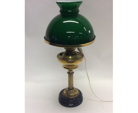 A brass mounted oil lamp with green shade. Est. £30 - £40.
