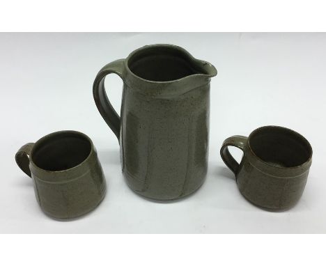 DAVID LEACH: A tapering pottery water jug together with two matching mugs. Est. £25 - £35.