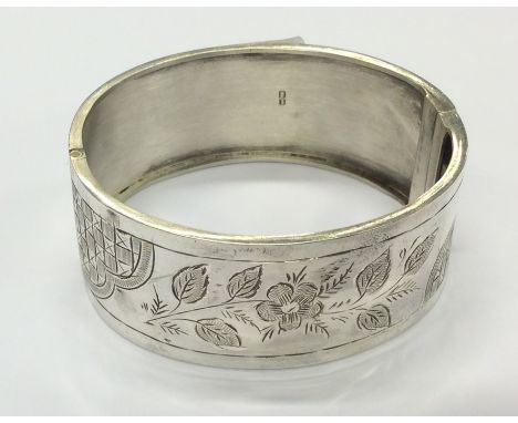 A hinged silver bangle with leaf decoration and concealed clasp. Approx. 24 grams. Est. £30 - £50.