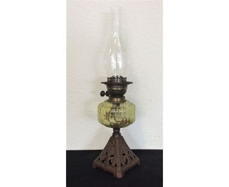 An oil lamp decorated with cast base. Est. £25 - £35.