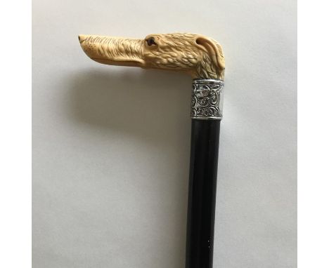 A good carved walking stick in the form of a greyhound with silver band. Est. £40 - £60.