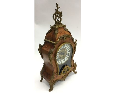 A French mantle clock decorated with ormolu mounts and scroll feet. Approx. 58 cms high. Est. £100 - £200.