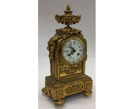 A French brass mantle clock attractively decorated with scrolls, flowers and gargoyle sides with white enamelled dial. Approx