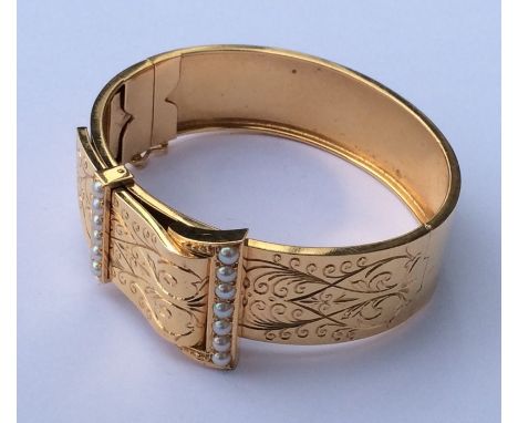 A high carat gold French pearl hinged bangle with concealed clasp engraved with swags and scrolls. Approx. 35 grams. Est. £10