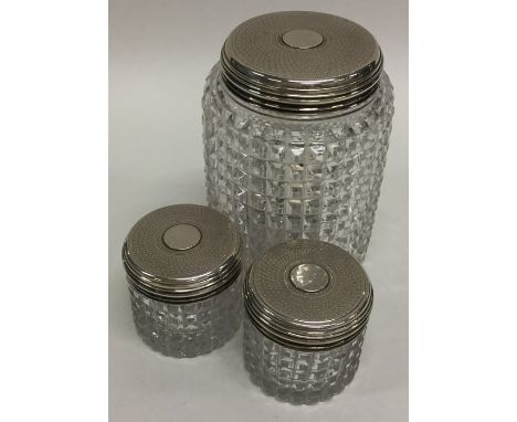 A garniture of three silver topped hobnail cut dressing table jars with engine turned decoration. Est. £30 - £50.