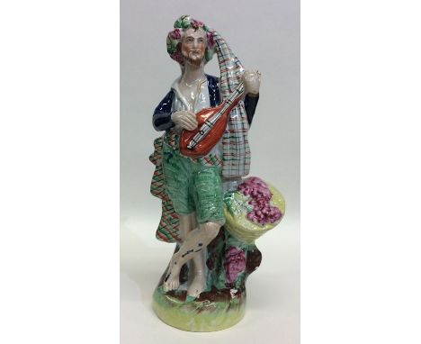 A tall Staffordshire figure of a gentleman playing mandolin. Approx. 22 cms high. Est. £30 - £40.