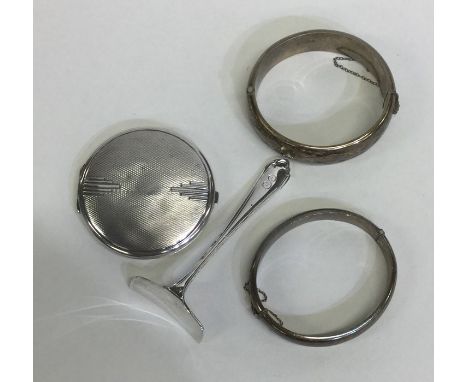 A silver compact together with a silver bangle, pusher etc. Approx. 110 grams. Est. £20 - £30.
