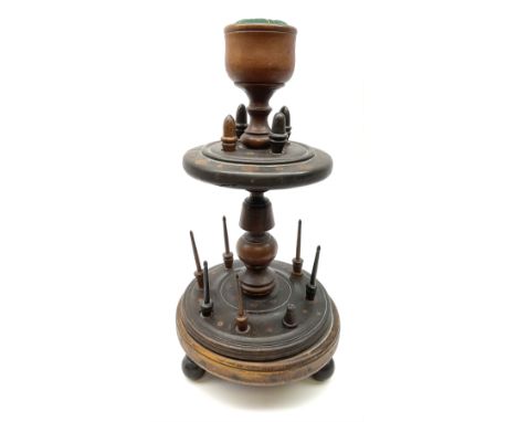 A 19th century turned oak and fruitwood bobbin stand, upon three turned feet supporting a stepped lower platform with spindle