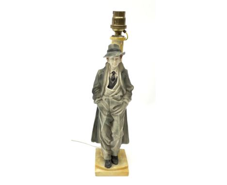 A moulded resin table lamp, modelled as a man in 1940s dress leaning against a lamp post, including fitting H32cm.