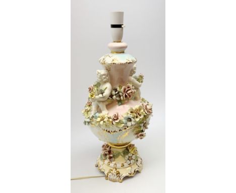 An Italian Capodimonte style lamp base, of pedestal urn form with applied putti and encrusted flower detail, heightened with 