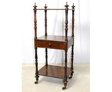 A 19th century rosewood three tier wot not, the turned uprights surmounted by finial's, the second shelf having a single draw