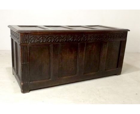 A 17th century oak coffer with four panel lid, candle box interior, carved decoration to the top rail above fluted muntins di