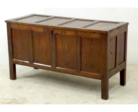 An 18th century oak coffer, the four panel lid above a conforming front, the top rail carved with the initials and date I.D. 