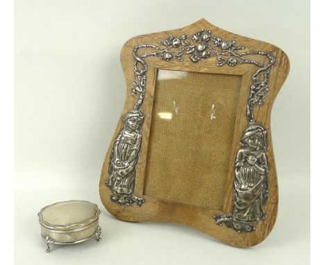An Arts & Crafts silver and oak photograph frame, Birmingham 1904, embossed with Kate Greenaway characters, 22 by 19cm, and a