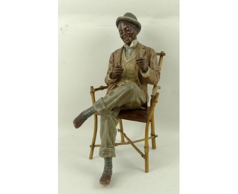 A Friedrich Goldscheider terracotta figure, circa 1890, modelled by Haniroff of a black man in a seated pose, impressed marks