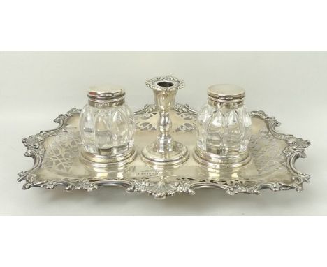 A Victorian silver desk stand with a pair of silver topped glass inkwells and a chamber stick on a pierced rectangular base w