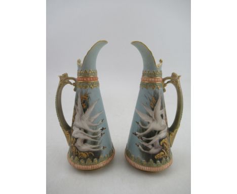 A pair of left and Right Royal Worcester jugs each decorated with four swans on a powder blue ground by George Johnson to ric