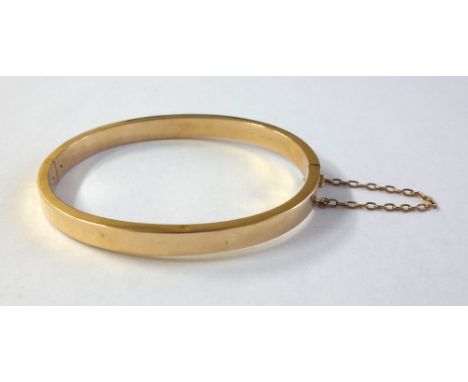 An early 20th century rose gold hollow hinged bangle of rectangular section, stamped '15', 8.5g.