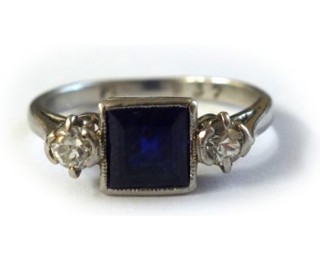 An early 20th century sapphire and diamond three stone ring, rub-over set at the centre with a square step-cut sapphire betwe