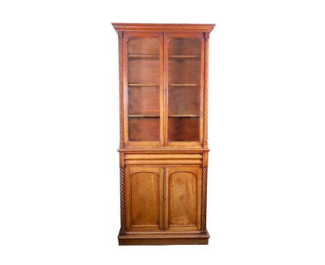 An early Victorian mahogany bookcase, the upper part enclosed by a pair of glazed doors between half round ropetwist pilaster