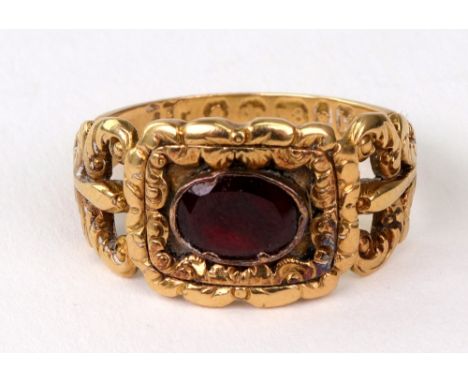 A George IV 18ct gold mourning ring, the oblong head later collet set with an oval garnet within a floral chased border, the 