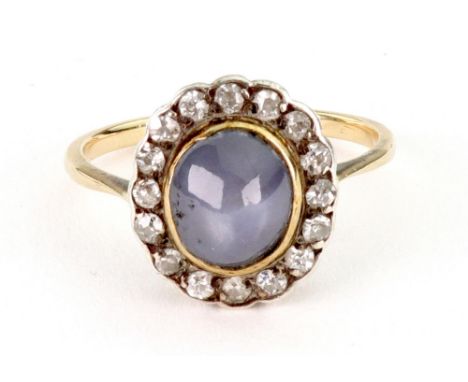 A diamond and star sapphire cluster ring, the pale blue oval cabochon sapphire within a single-cut diamond 16 stone surround,