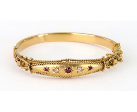 An early 20th century 15ct gold ruby and diamond hollow bangle, Birmingham 1908, star-gypsy set with three graduated round ru