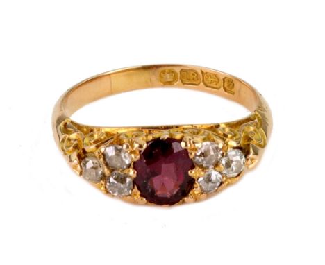 An 18ct yellow gold, ruby and diamond carved half hoop ring, Birmingham 1892, central oval mixed cut ruby between three-stone