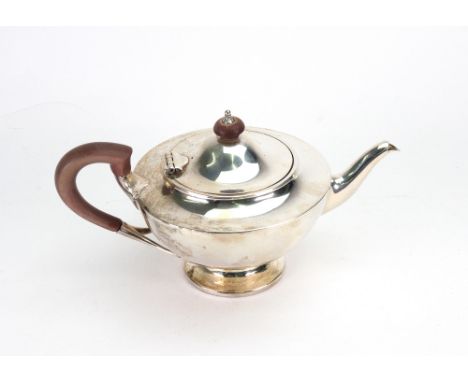 A bachelor Art Deco silver teapot, Goldsmiths & Silversmiths Company, London 1919, with wooden scroll handle and finial to th