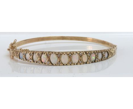 A cabochon opal and diamond hinged bangle, the eleven graduated cabochon opals divided by pairs of small brilliant-cut diamon