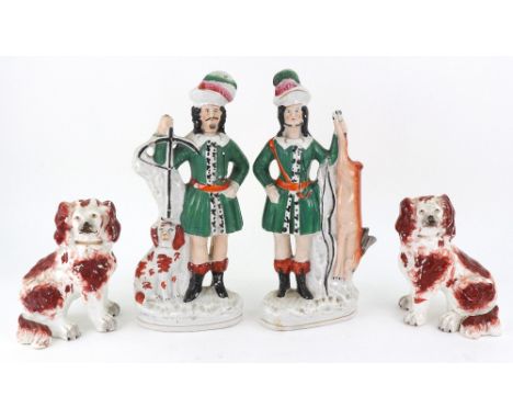 A pair of Staffordshire pottery figures of huntsman wearing plumed hats, one a King Charles Spaniel at his side, the other a 