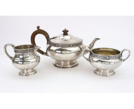 A three piece circular silver tea service, Mappin & Webb, London 1929, with 'Celtic borders', on stepped spreading bases, the