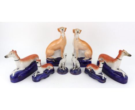 Two pairs of Staffordshire recumbent whippets on cobalt blue pen holder bases, 18.5 and 12cm wide respectively, a pair of sim