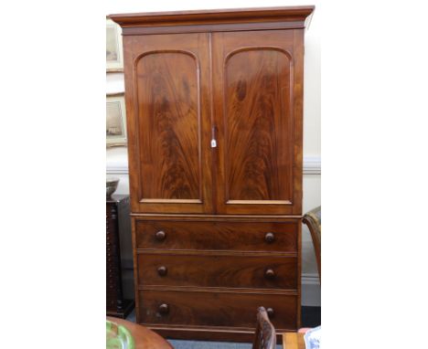 A Victorian mahogany linen press, circa 1860, the moulded cornice above sliding trays enclosed by a pair of arched panel door