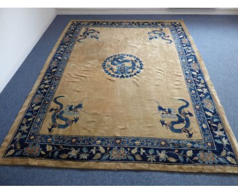 A circa 1900 Peking carpet: beige ground with a central stylised cobalt blue five-clawed dragon facing within a ruyi border a